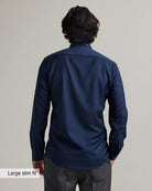back view of a man wearing a navy blue merinowool dress shirt in slim fit on a plain background