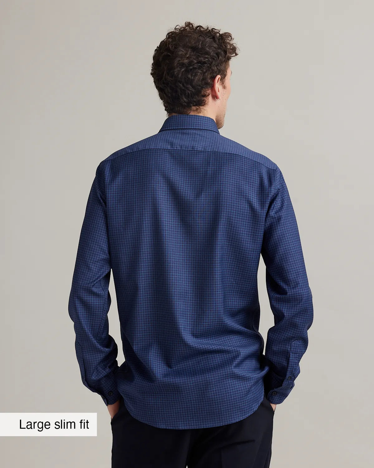back view of a slim fit navy blue merino shirt with graph check pattern and button down collar against a grey background