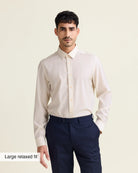 Man wearing a white merinowool dress shirt from Wolk in relaxed fit with navy trousers on a beige background