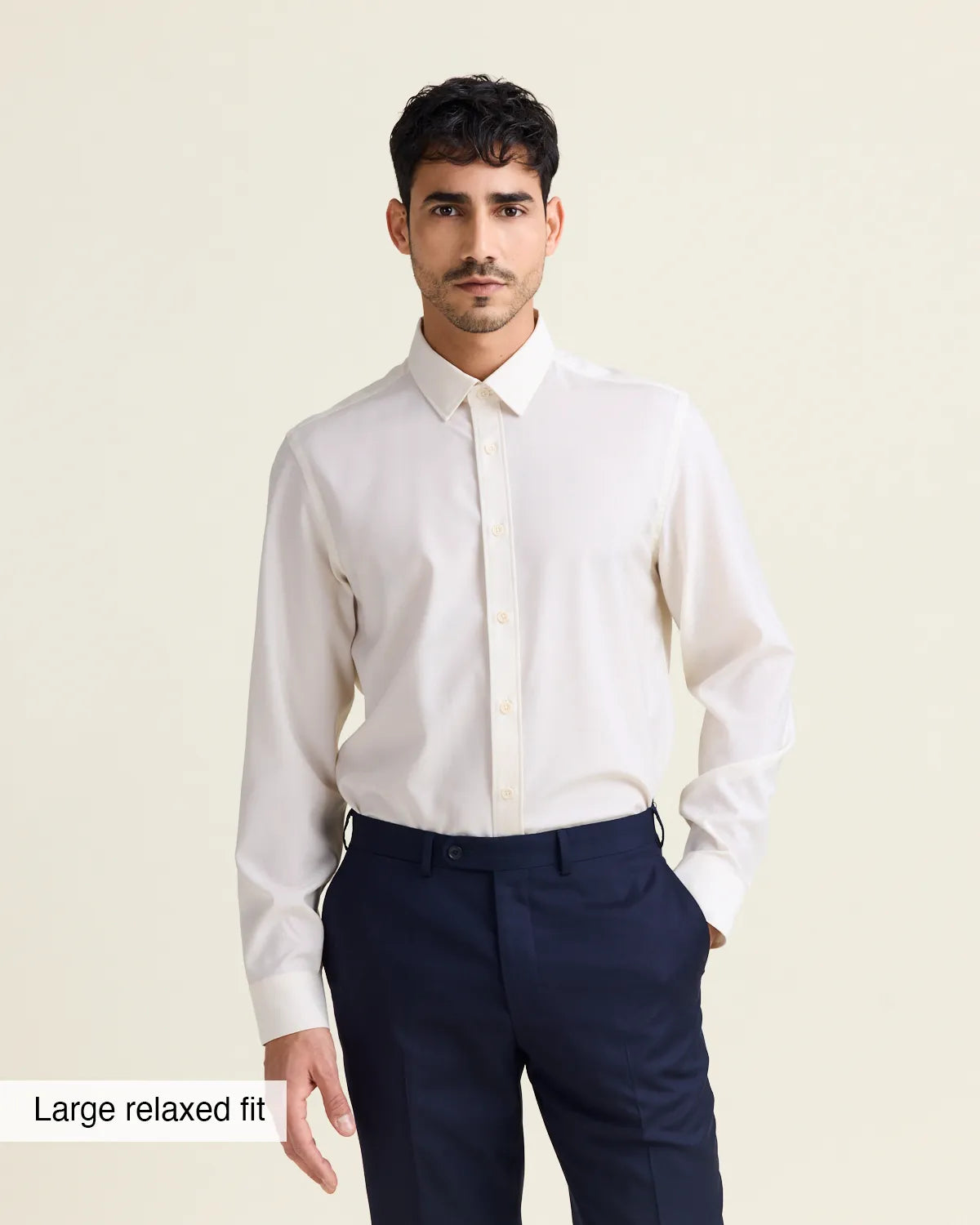 Man wearing a white merinowool dress shirt from Wolk in relaxed fit with navy trousers on a beige background