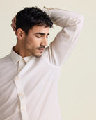 man doing a smell test under his armpit wearing a white merinowool dress shirt 