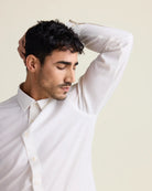 man doing a smell test under his armpit wearing a white merinowool dress shirt 