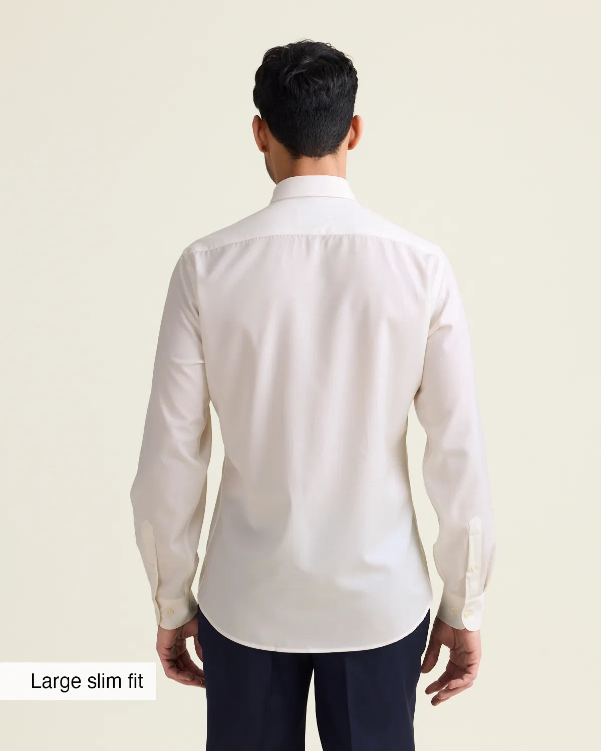 Man wearing a white merino dress shirt with in slim fit showing the untucked back of the shirt