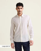 Man wearing a white merinowool dress shirt from in slim fit with navy trousers on a beige background