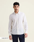 Man wearing a white merinowool dress shirt from in slim fit with navy trousers on a beige background