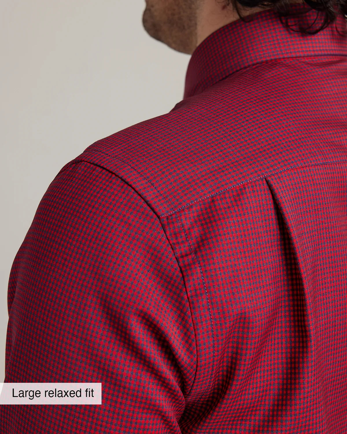 detail of the shoulder and back pleat on a red/navy gingham button down shirt in merino wool