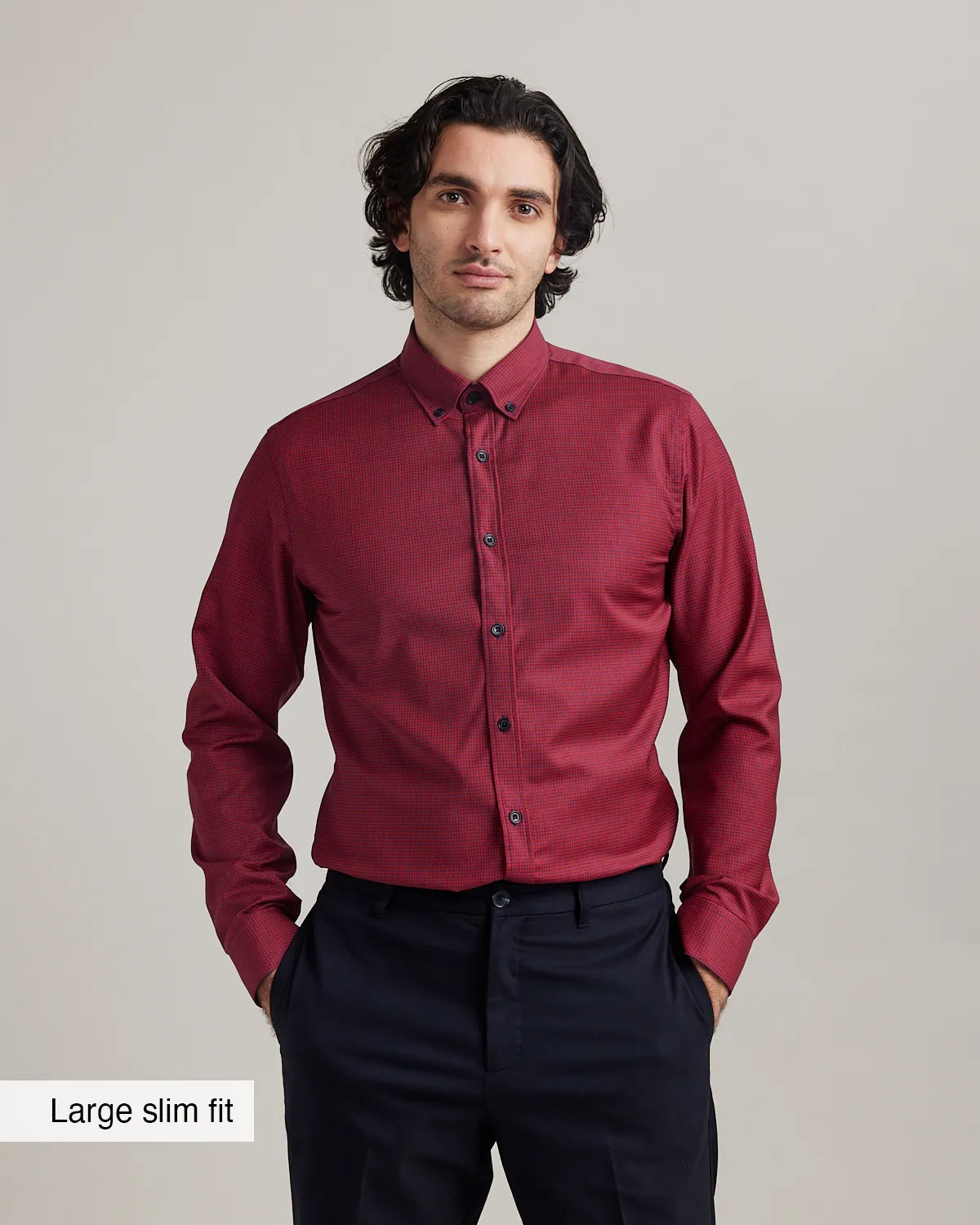 man wearing a red merino button-down shirt from Wolk in slim fit on navy trousers against a gray background