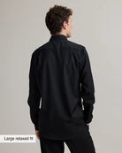 Man wearing a black merinowool shirt with a large relaxed fit label on a gray background