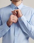 man adjusting the cuff on a light blue merino wool dress shirt 