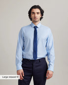 Man wearing a light blue merino wool dress shirt and dark blue tie with text 'Large relaxed fit' on a gray background