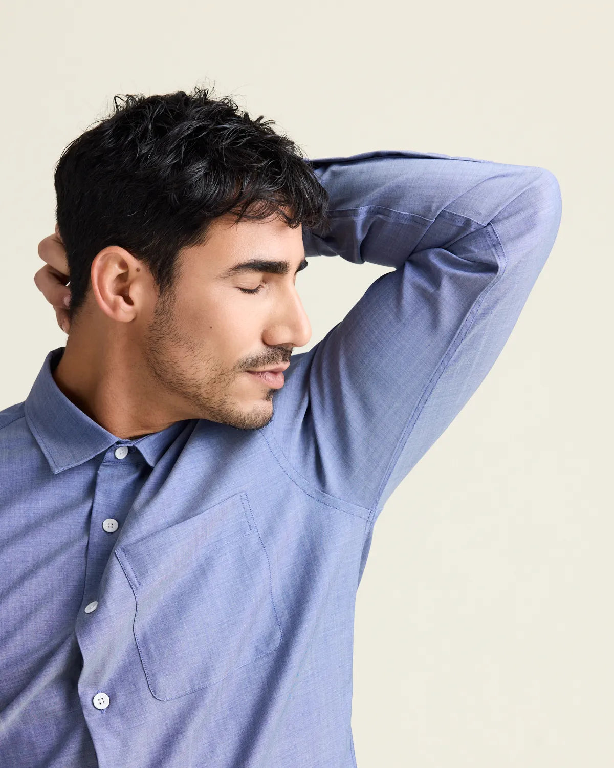 man smelling his fresh armpit wearing a light blue denim merinowool shirt from the brand Wolk