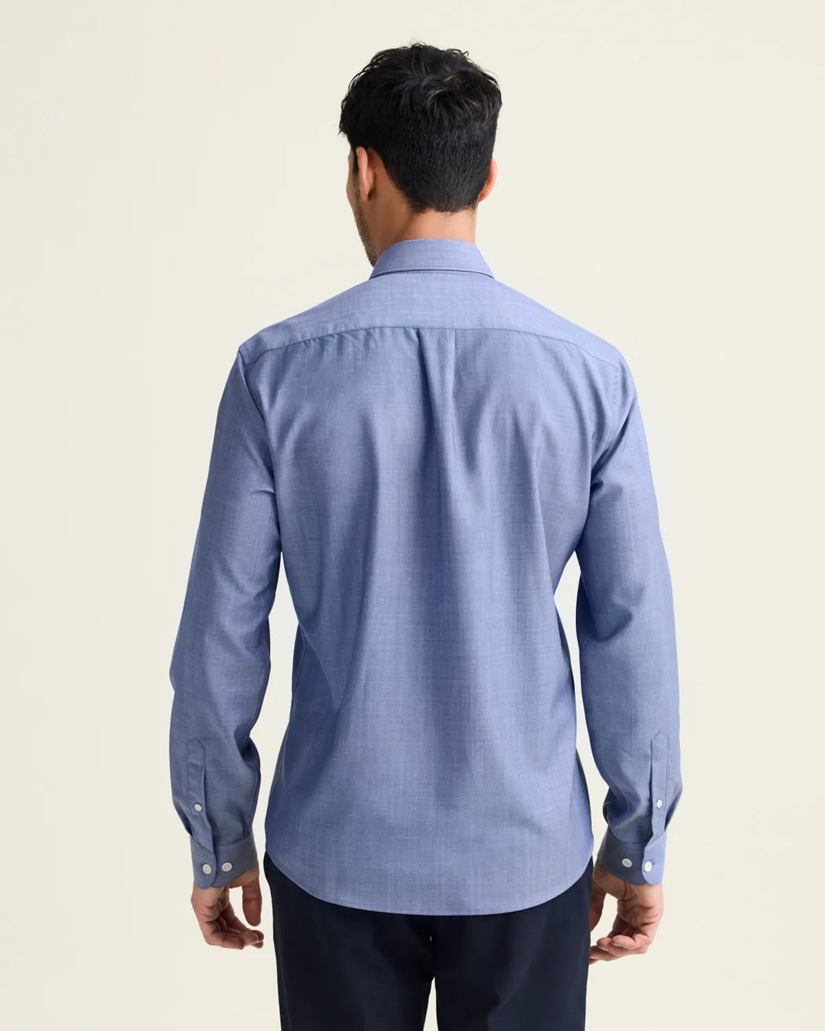 back view of a man wearing an untucked light blue denim merinowool button up shirt 
