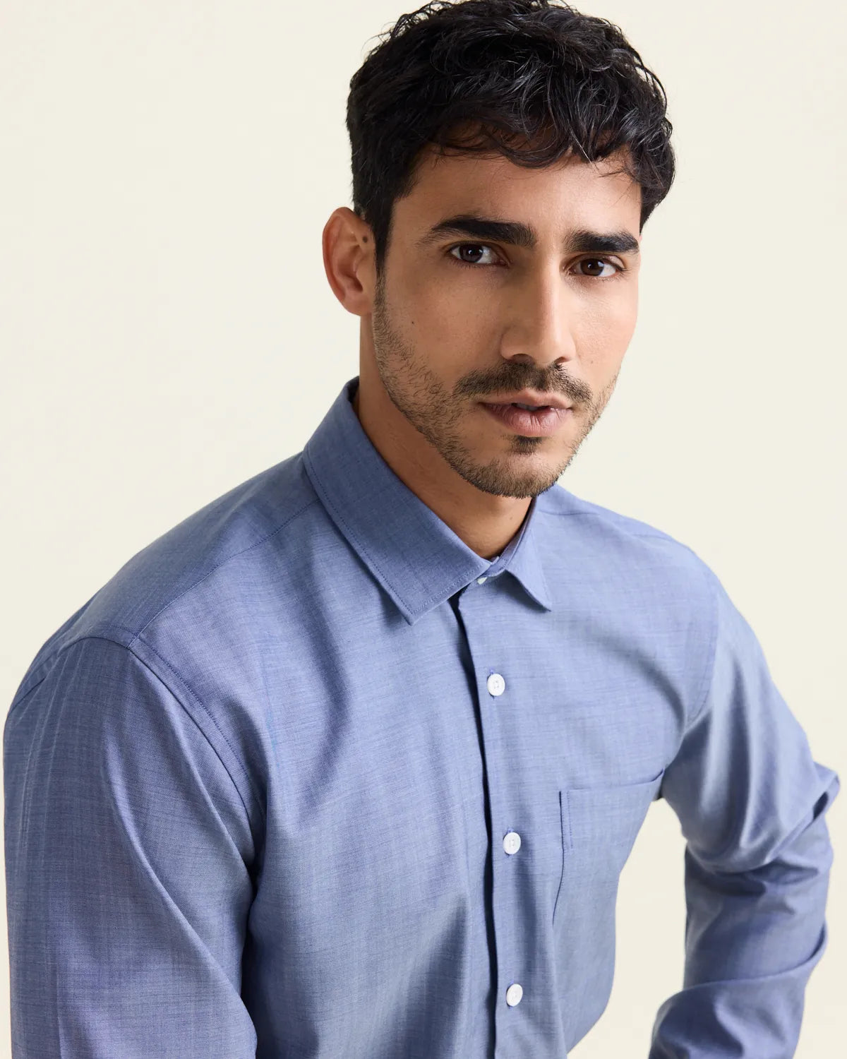 close up of a man wearing a light blue denim merinowool shirt with white buttons highlighting the face and the collar