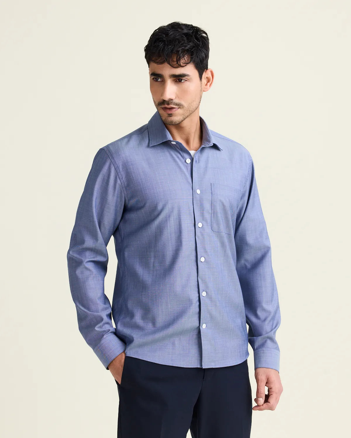 Man wearing a light blue denim merinowool shirt against a beige background