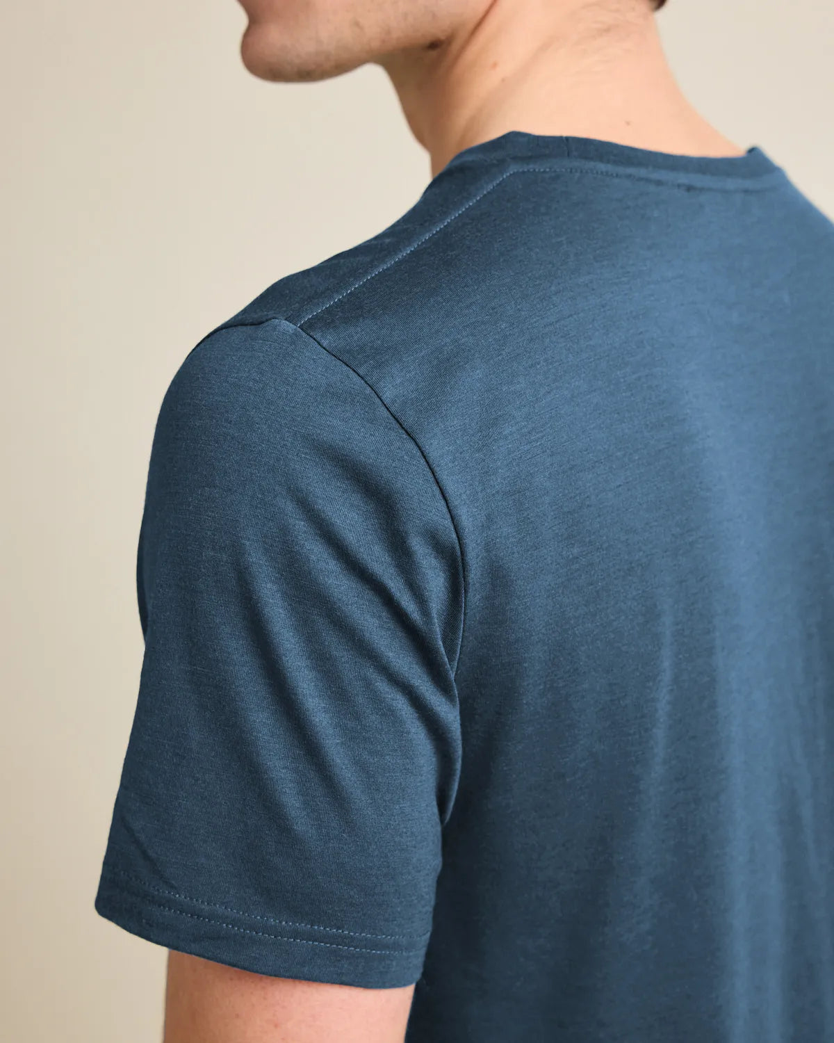 Shouldr detail of a denim-blue merino t-shirt against a beige background