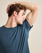 Male model smelling the fresh armpit of his denim-blue merino t-shirt