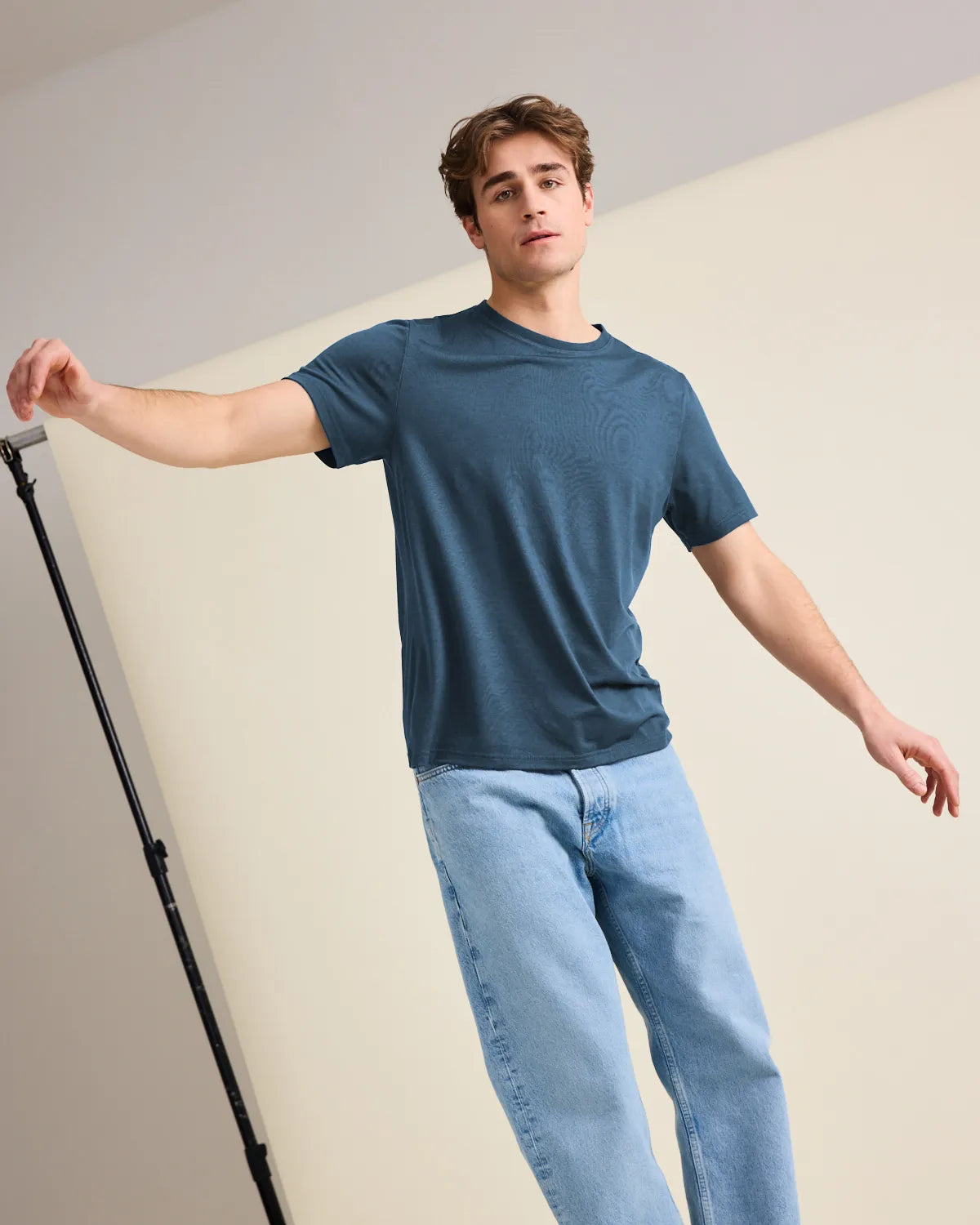 Man wearing a merinowool blue t-shirt and light blue jeans balancing in a photostudio