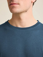 Close-up view of the collar of a denim blue men's merino wool T-shirt by Wolk, showcasing European craftsmanship.