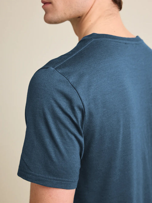 Shoulder detail of a men's denim blue merino wool T-shirt from Wolk, emphasizing fine stitching and quality.