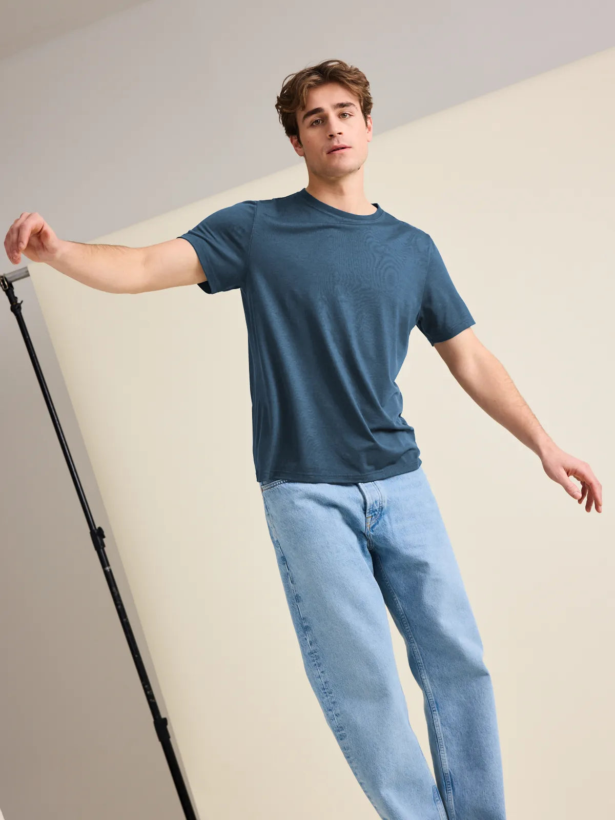 European-crafted, denim blue merino wool T-shirt for men worn by a male model balancing in the studio.