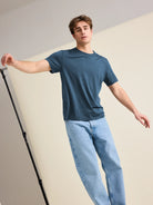 European-crafted, denim blue merino wool T-shirt for men worn by a male model balancing in the studio.