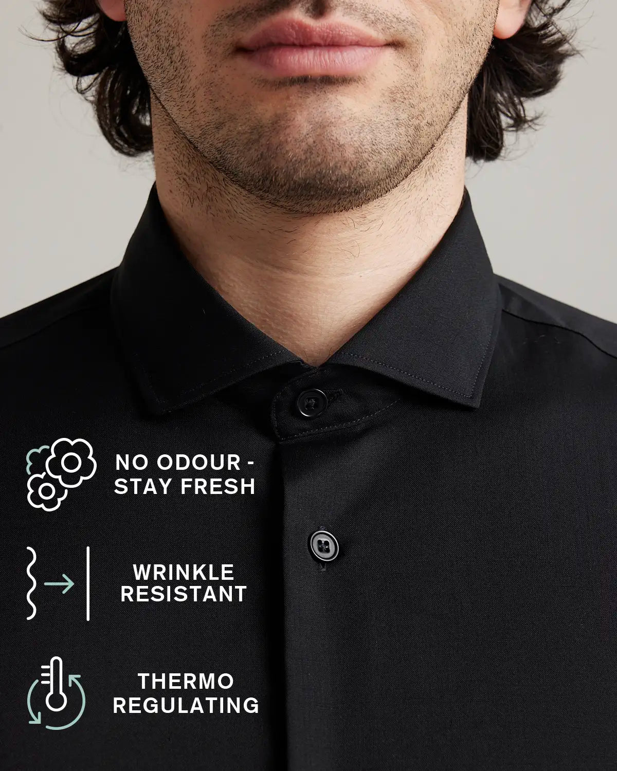 Close-up of a black merino dress shirt with text highlighting features like no odor, wrinkle resistance, and thermo regulation.