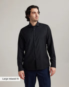 Man wearing a black merino dress shirt with a large relaxed fit label on a gray background