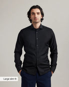 Man wearing a black merinowool formal shirt with 'Large slim fit' label on a gray background.