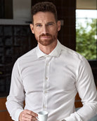 Man in a white merino wool formal shirt from Wolk shirt holding a coffee cup indoors