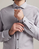 man adjusting the button on the cuff of a light grey heather merino wool dress shirt with a cut-away collar 