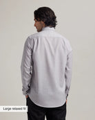 Back view of a man wearing a light gray dress shirt in relaxed fit with a subtle pattern on a plain background