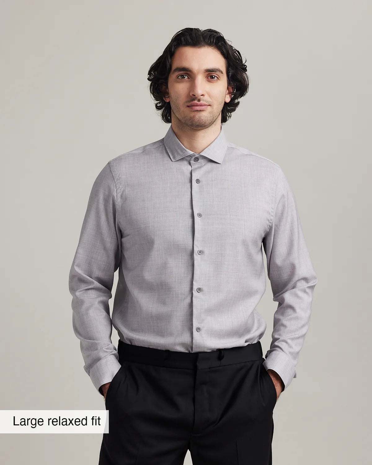 Man wearing a light gray merino dress shirt with a subtle heather pattern on a plain background