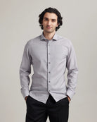 Man wearing a light grey merino wool dress shirt from Wolk with a subtle heather pattern on a plain background