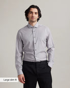 Man wearing a light gray merino wool dress shirt and black pants on a plain background