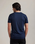 Back view of a man wearing a navy blue merino t-shirt against a plain background