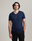 Man wearing a navy blue merino wool V-neck t-shirt from Wolk against a plain background