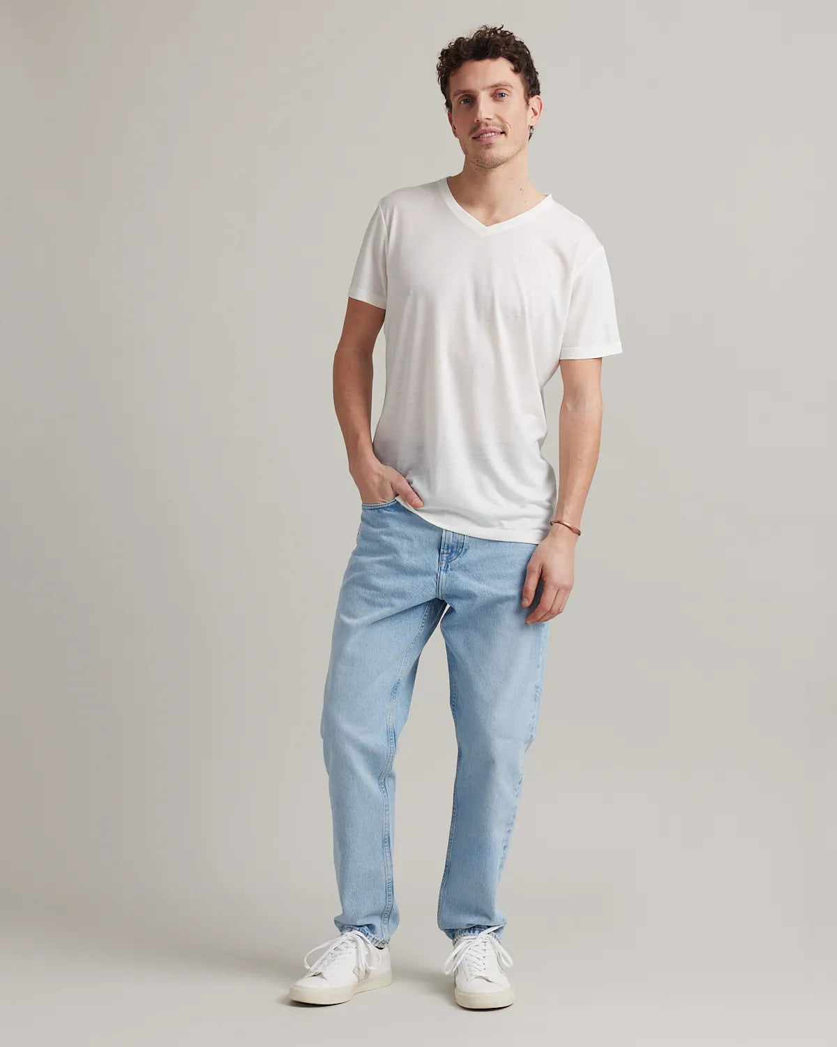 Man wearing a white merino wool t-shirt and light blue jeans in a photo studio
