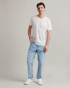 Man wearing a white merino wool t-shirt and light blue jeans in a photo studio