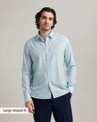 Man wearing a light blue merinowoo dress shirt with a large relaxed fit label on a plain background