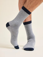 Gray merino wool socks with navy accents worn by a man with ventilation and rib texture