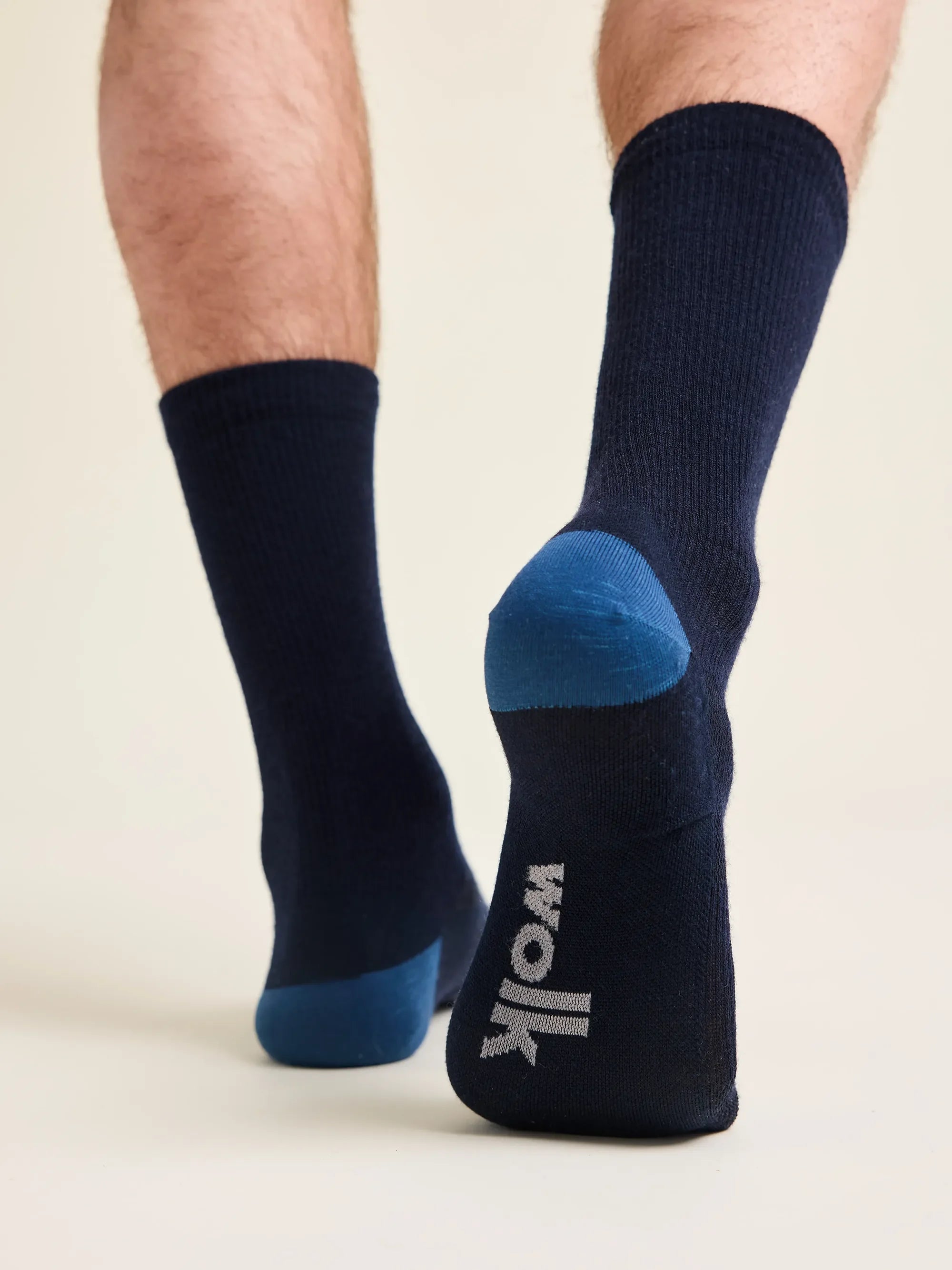 Wolk merino wool socks worn by a man in navy color with blue heel and toe and Wolk logo in light grey on the foot bed