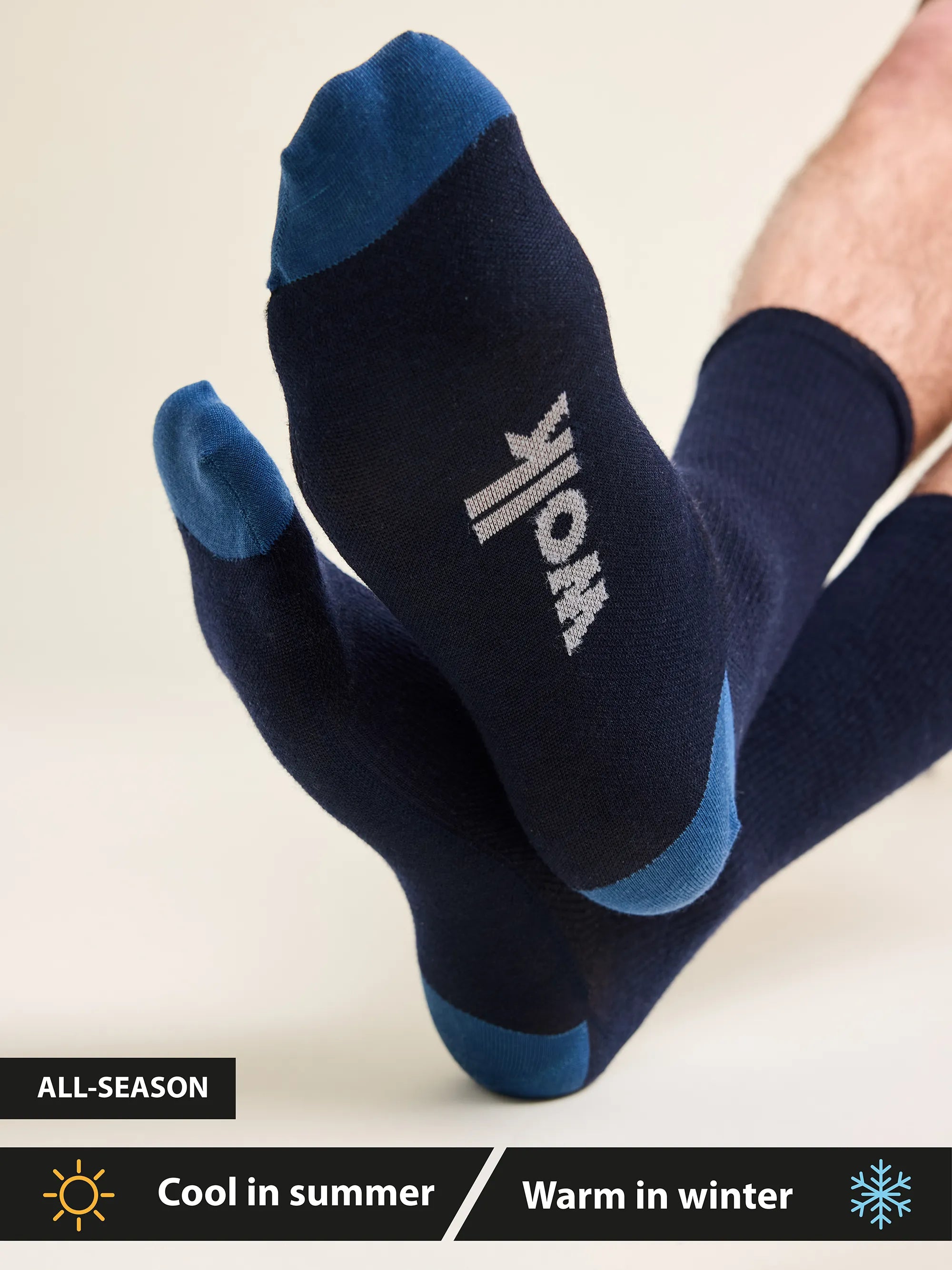 Merino wool socks worn by a man labeled cool in summer and warm in winter in navy color with Wolk logo on the foot bed