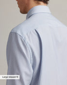 clowse up of the shoulder and back pleat on a light blue striped merinowool shirt with a label on the image stating Large relaxed fit