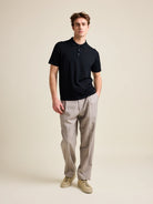 Model wears a black merino wool polo shirt with short sleeves.