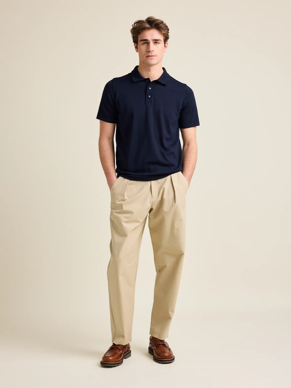 Man wears short sleeve merino wool polo from Wolk in dark navy blue color with 3 buttons and regular collar.