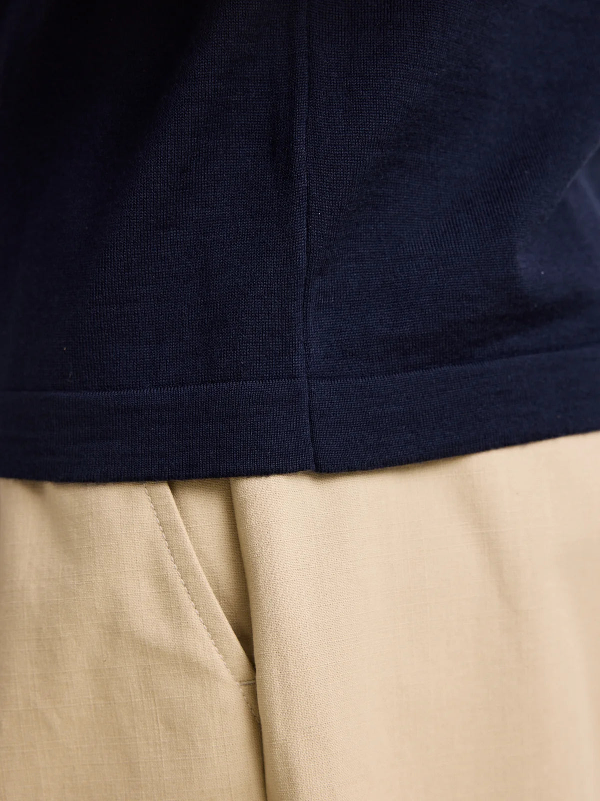 Detail of the rib knitting on the hem of a dark navy men's merino wool polo shirt from the European brand Wolk, showcasing the Zegna Baruffa Cashwool quality.