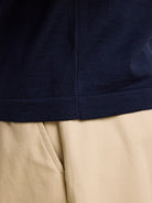 Detail of the rib knitting on the hem of a dark navy men's merino wool polo shirt from the European brand Wolk, showcasing the Zegna Baruffa Cashwool quality.