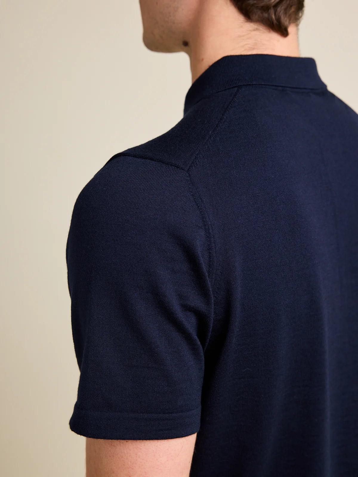 Shoulder detail of a men's darknavy blue merino wool Polo shirt from Wolk, emphasizing fine knitting and Cashwool quality.