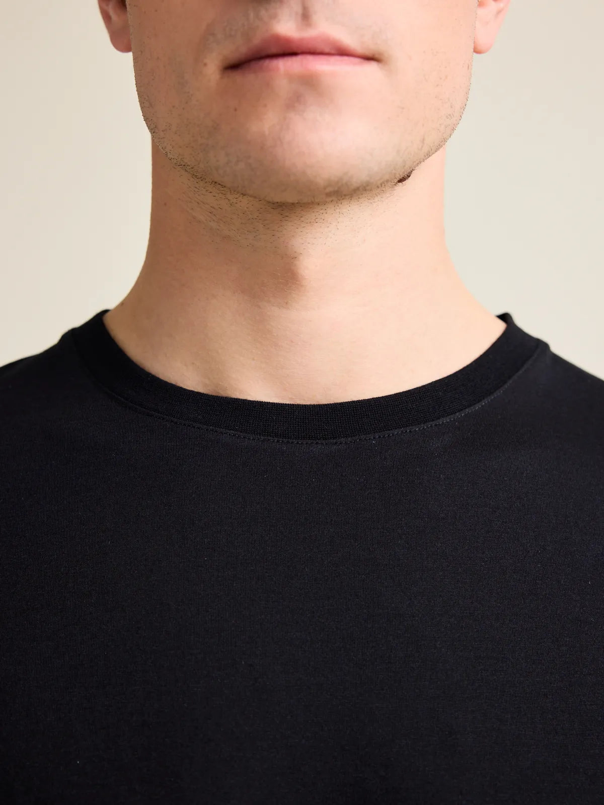 Detail of the crew neck on Wolk's black merino wool T-shirt for men, highlighting premium fabric.