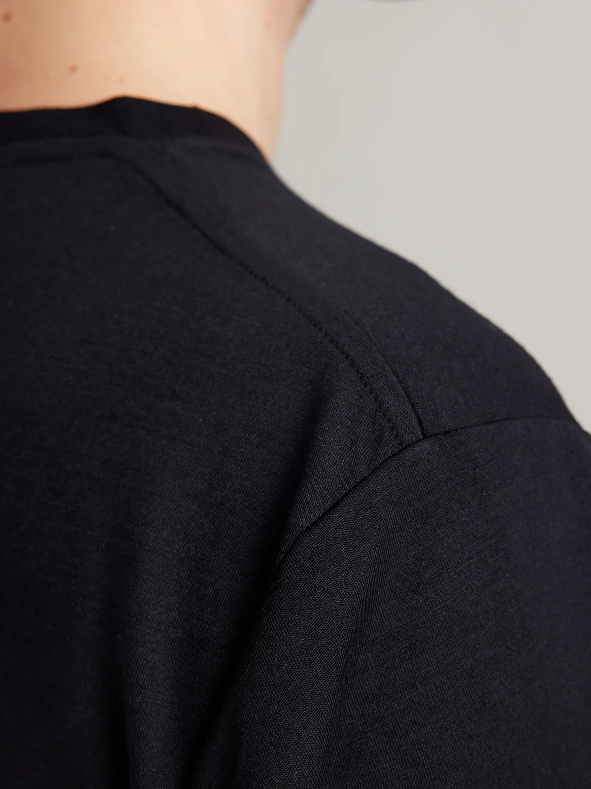 Shoulder detail of a men’s merino wool T-shirt in black from the Wolk Brand.